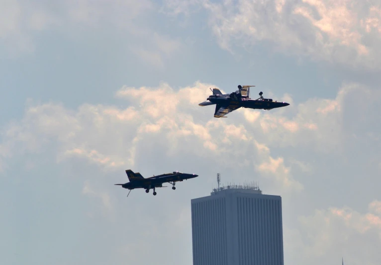 two fighter jets flying through the air in front of a building