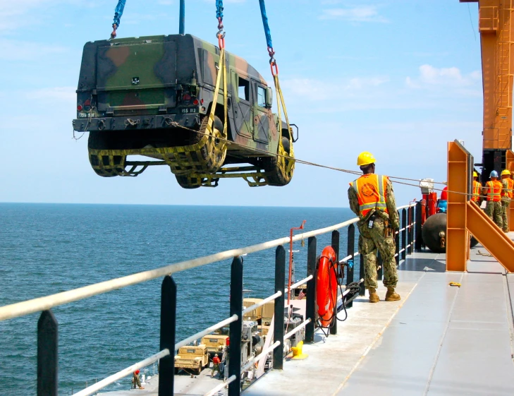 a military truck hanging over the edge of a boat