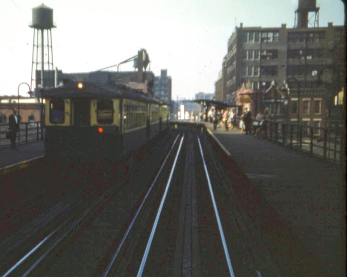 an old train going down some tracks next to buildings