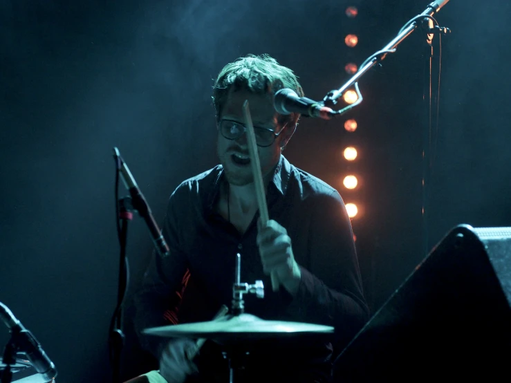 a young man playing a drum set on stage