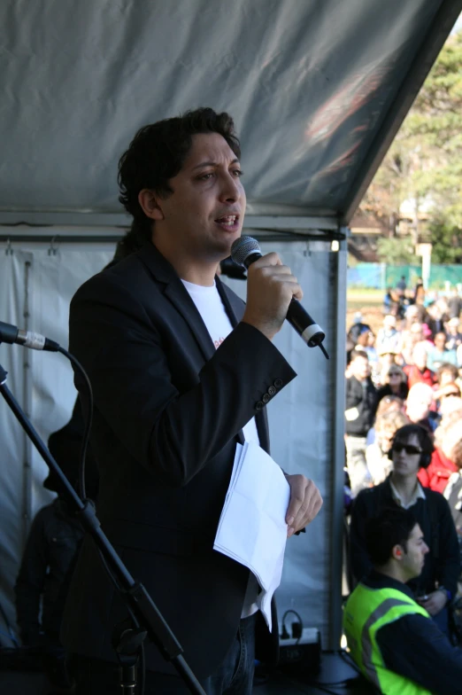a man is speaking into a microphone in front of a crowd