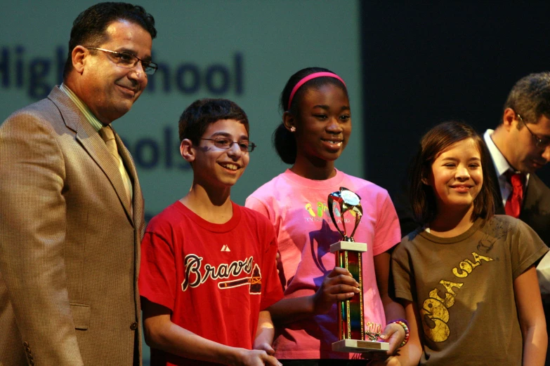 a group of young children holding onto a trophy