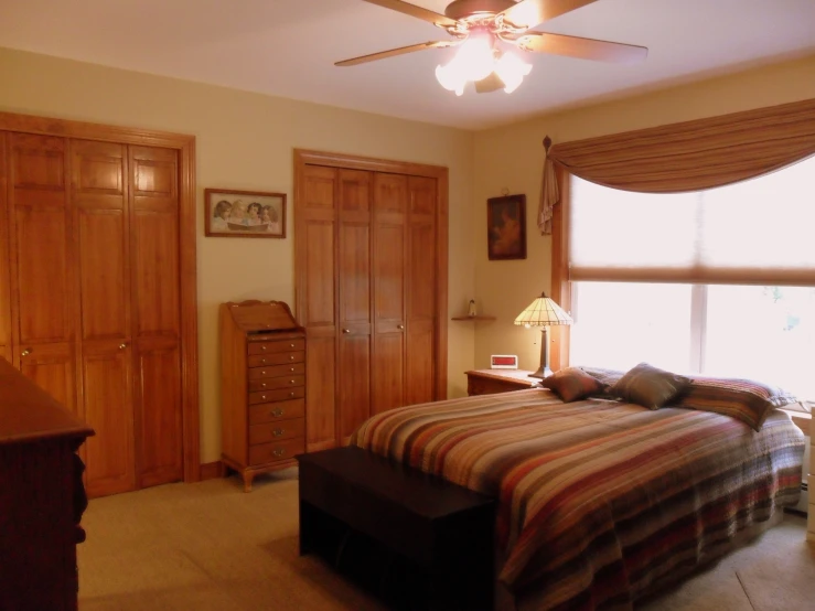 a bedroom with a bed, dresser and two windows