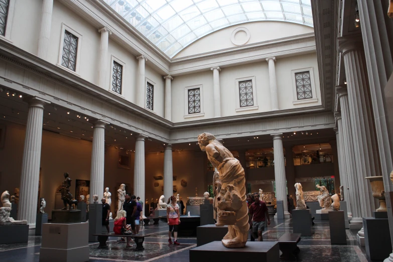 many people are looking at various sculptures in the museum