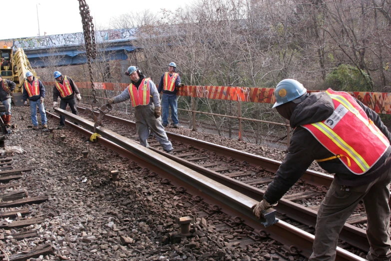 several construction workers are working on an old track