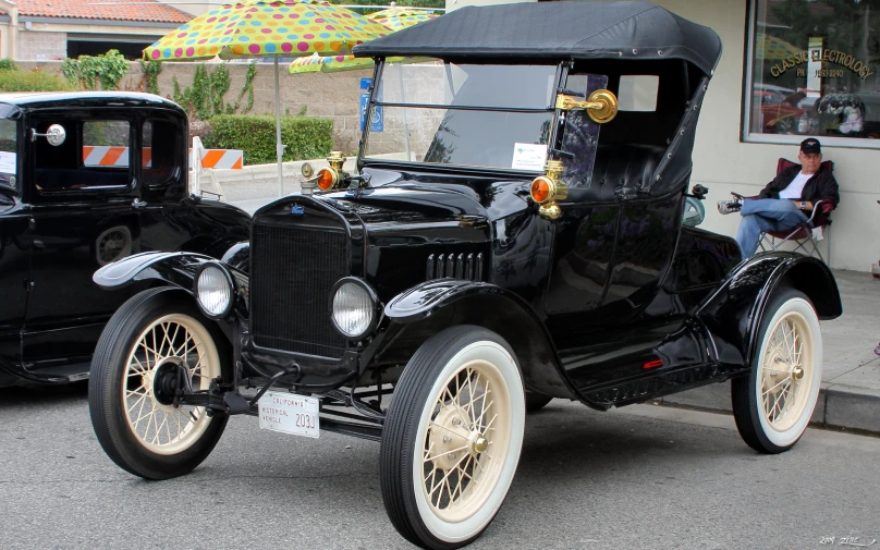 an old model black car sitting in front of a person