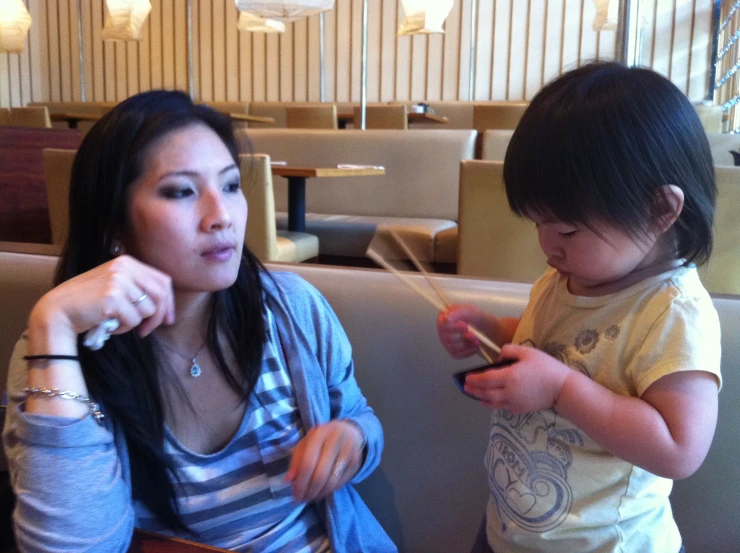 a woman and child sitting down with electronic devices