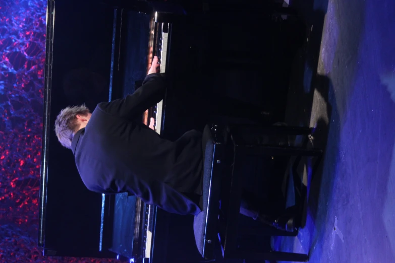 the man sits at a piano in front of purple background