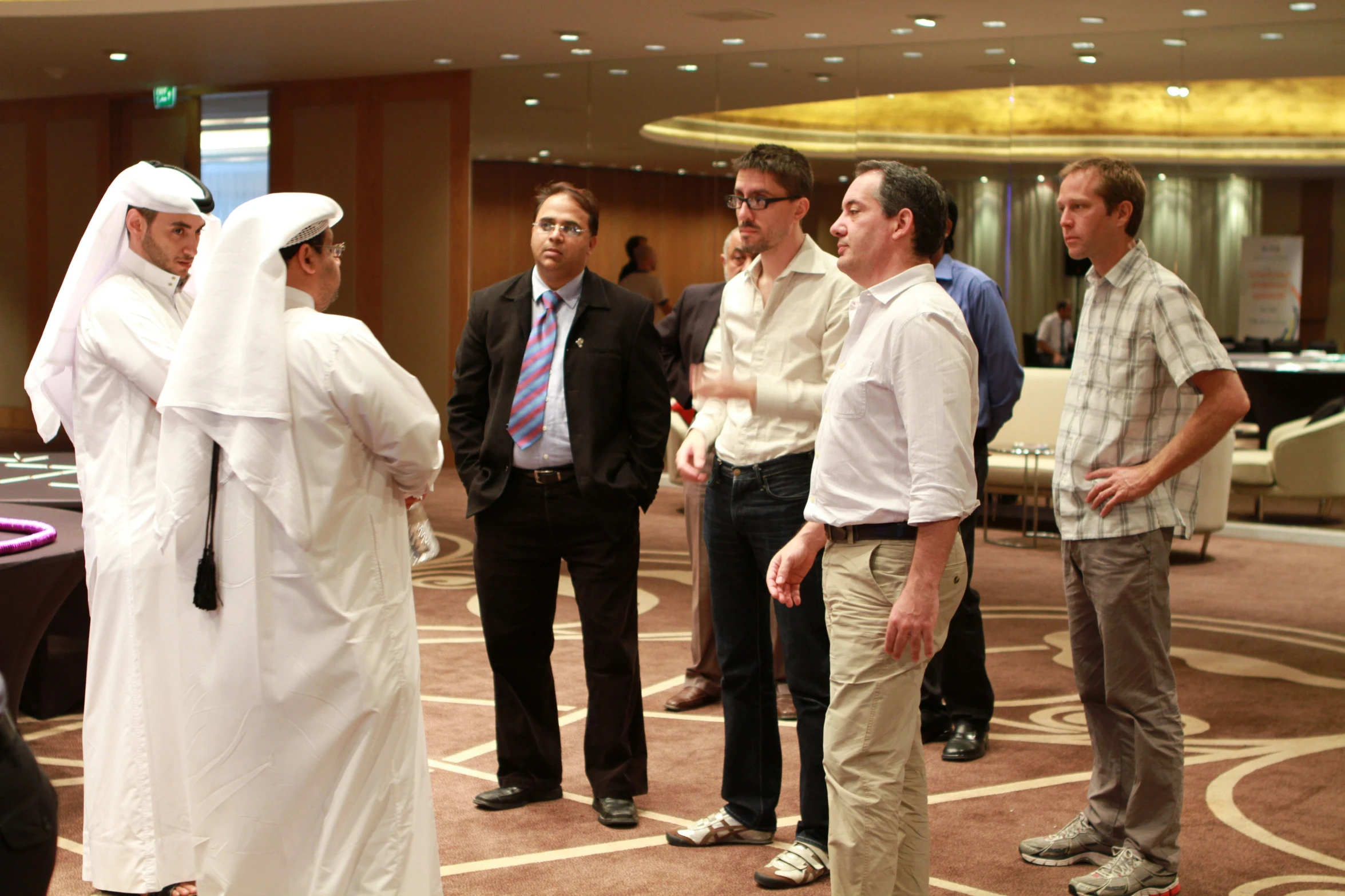 a man wearing a white hijab looks on while his colleagues talk