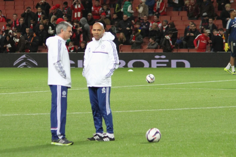 a man standing next to another person near soccer balls