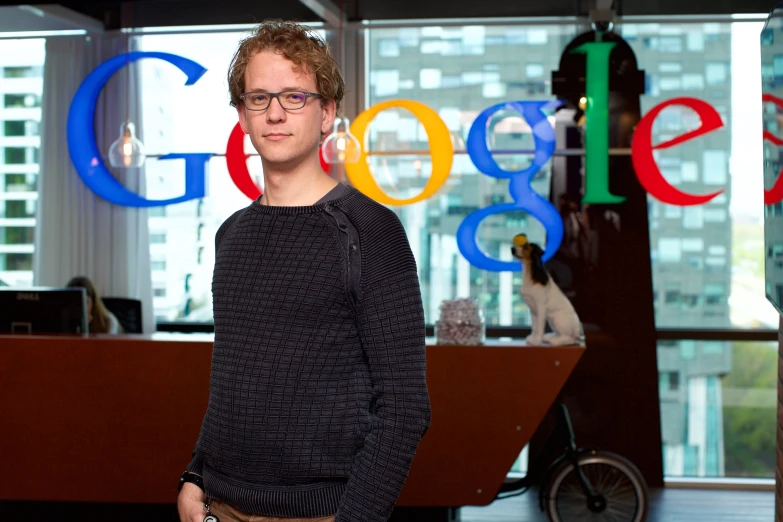 a man stands in front of the logo for the google company