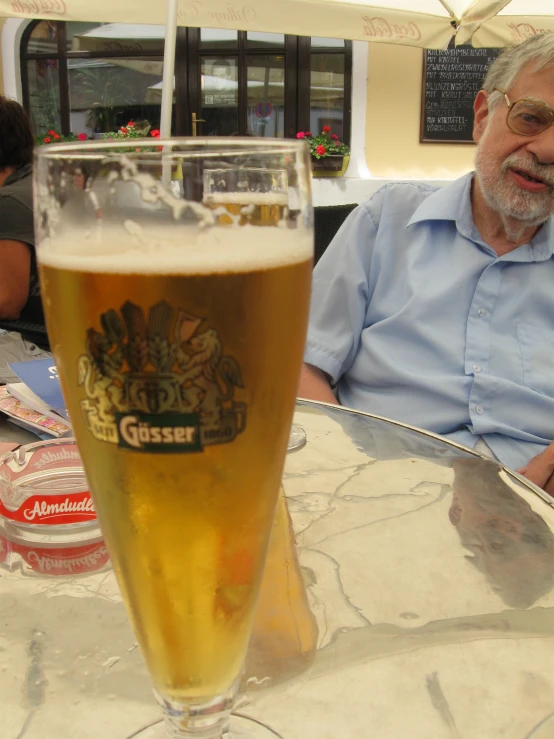 the man is sitting at a table with a beer in front of him