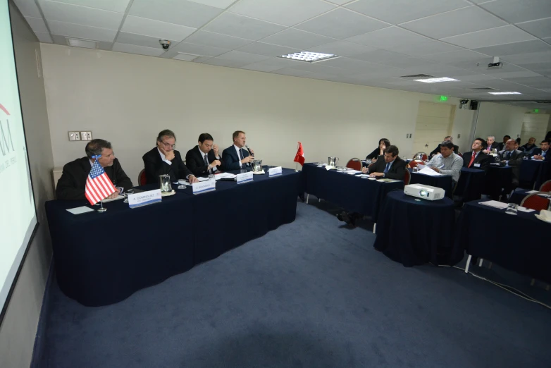 people sitting at a round table with a projector screen in front of them