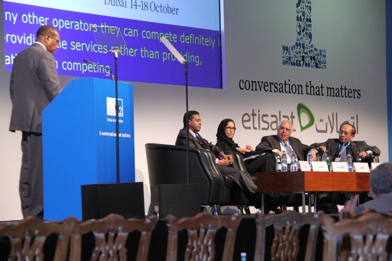 four people sitting at table during conference listening to the speaker