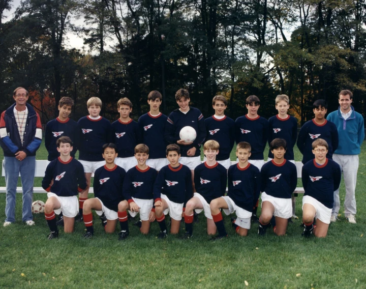 several s are posing with soccer balls in front of trees