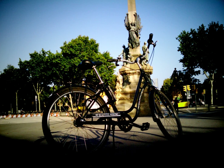 a bicycle leaning against a pedestal near trees