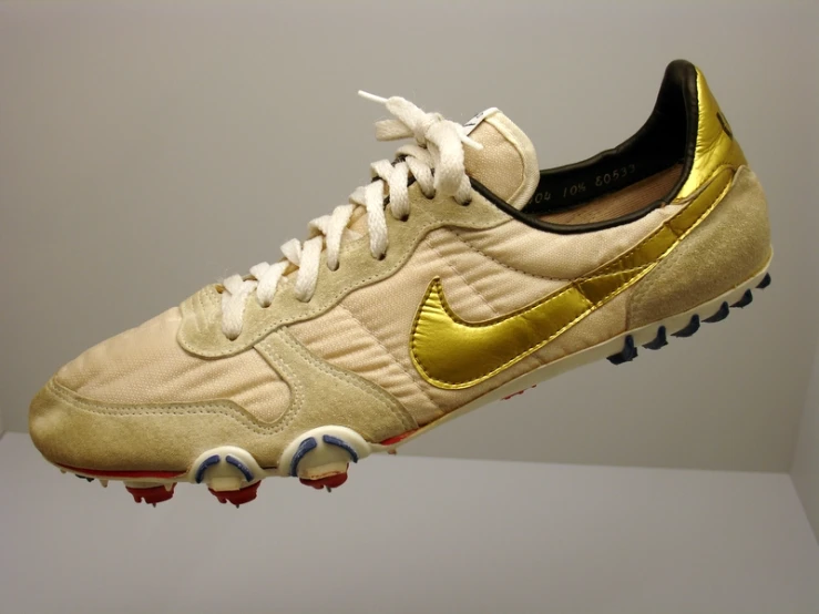 a pair of beige and gold nike soccer shoes