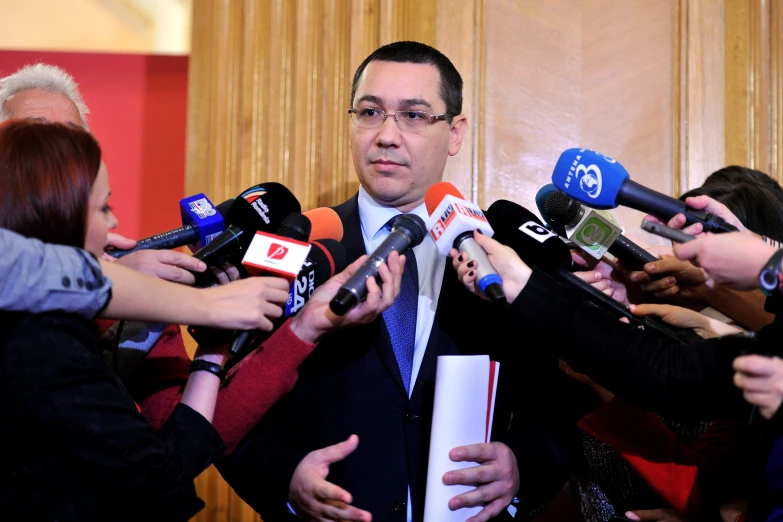 man in business suit surrounded by reporters and reporters