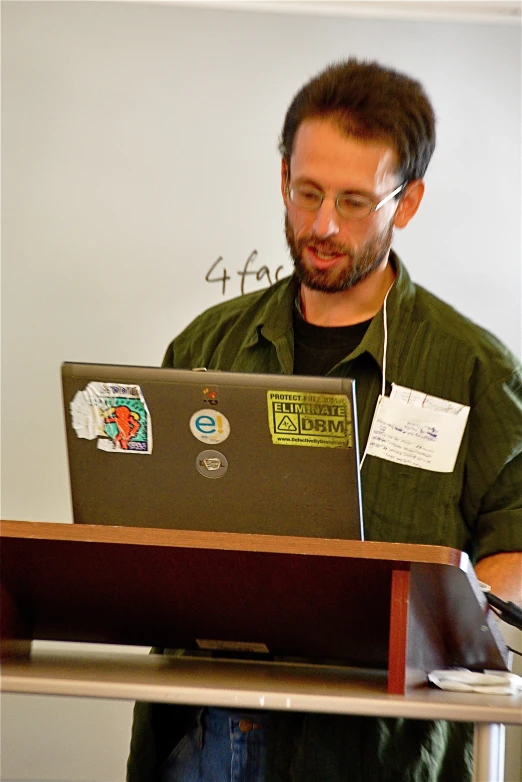 a man in glasses, green shirt and red pants works on a laptop