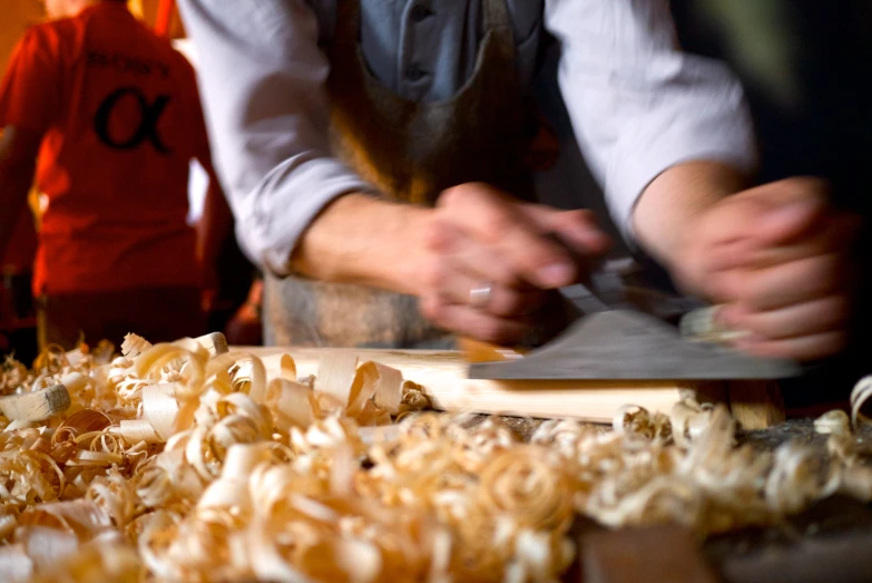 a pair of hands are carving a wooden object