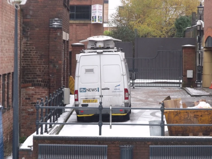 a white van is parked near a fence and buildings