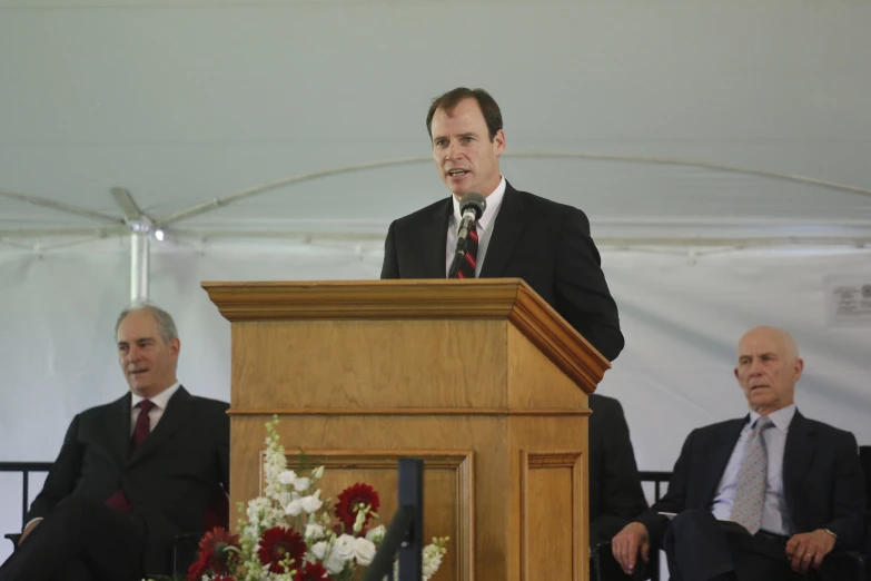 two men sitting behind a wooden podium talking