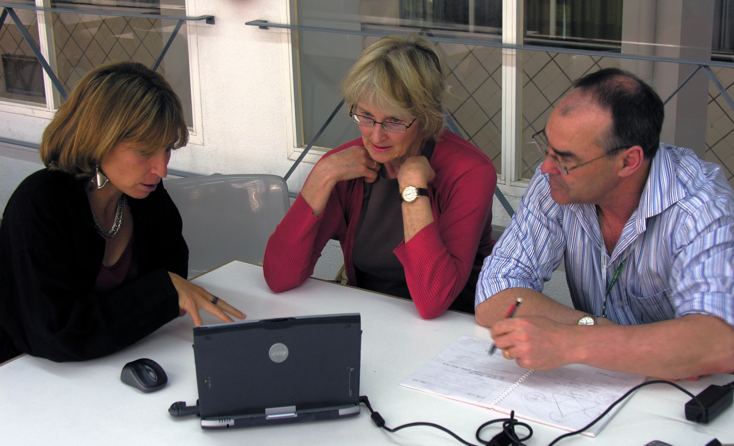 three people at a table with a computer