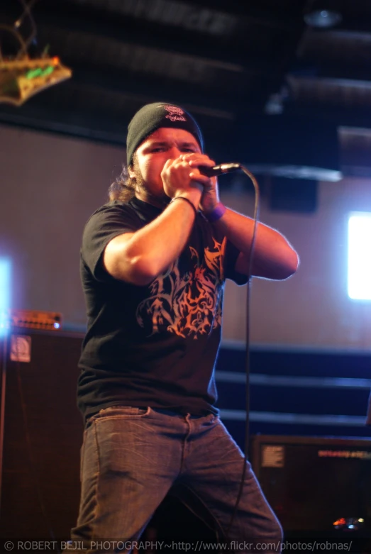 a man singing into a microphone with an american flag in the background