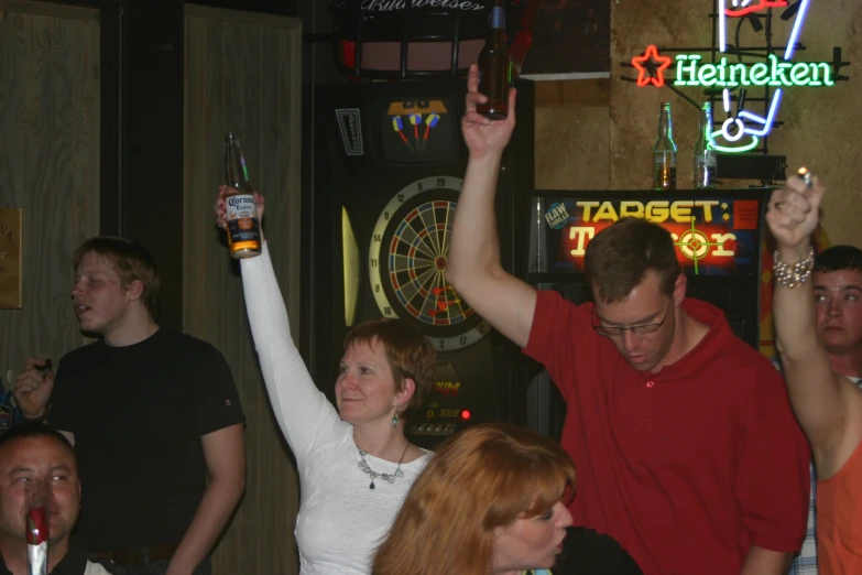 people in a bar with two men raising their hands in the air