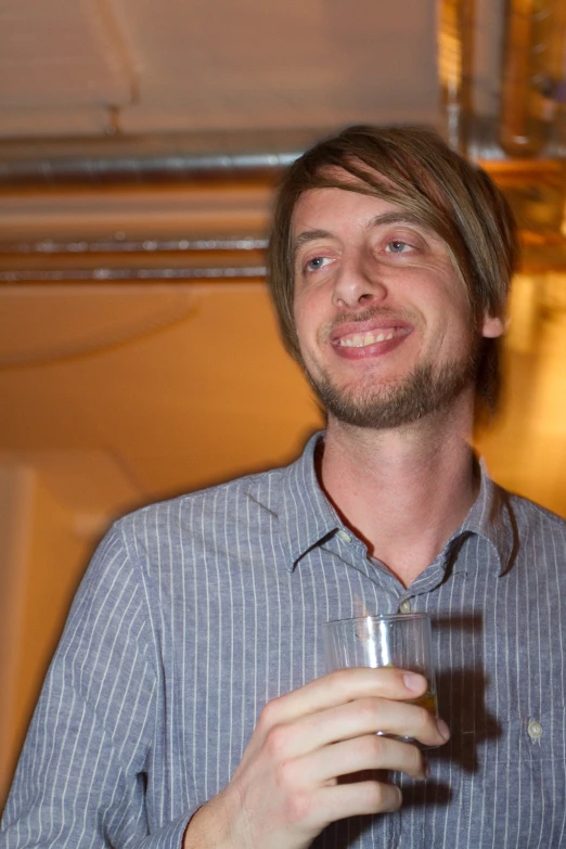 the man smiles holding a glass in his hand