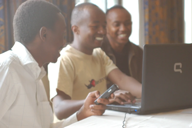 some children are sitting around a table looking at a cellphone