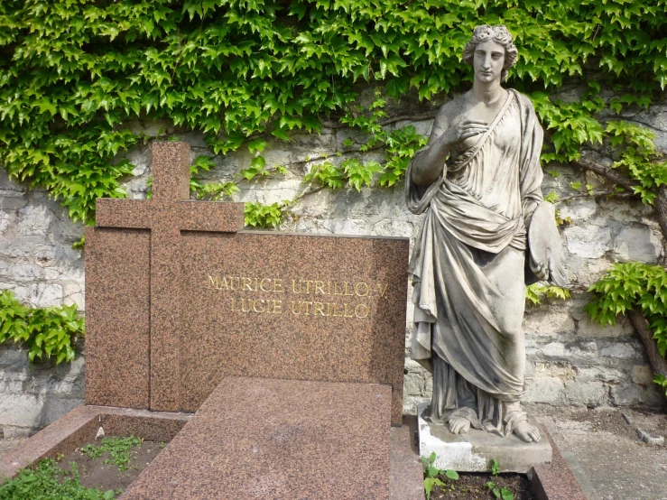 a statue stands next to the grave of an unknown man