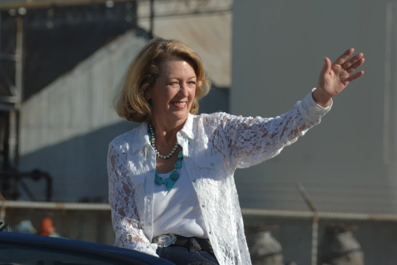 a woman waving and holding up her hand