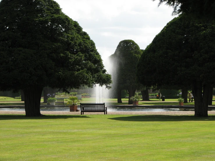 a park area with trees, a bench, and a fountain