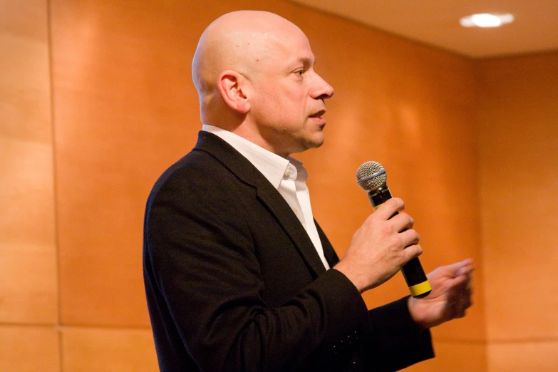 a bald man with a microphone in a room