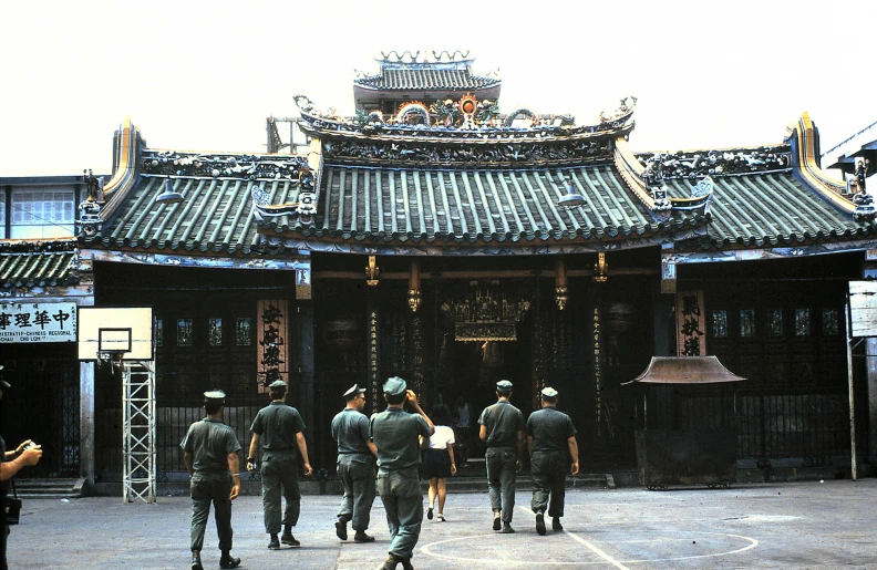 some soldiers walking towards a building and a camera man