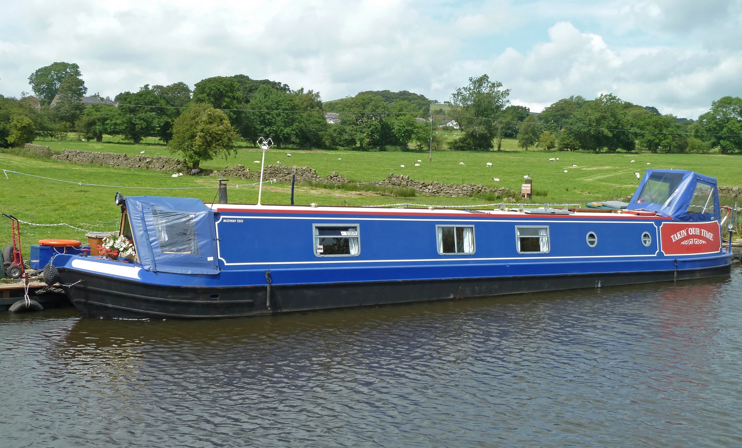 a blue house boat parked on the side of a river