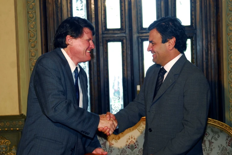 two men in business suits smiling and shaking hands