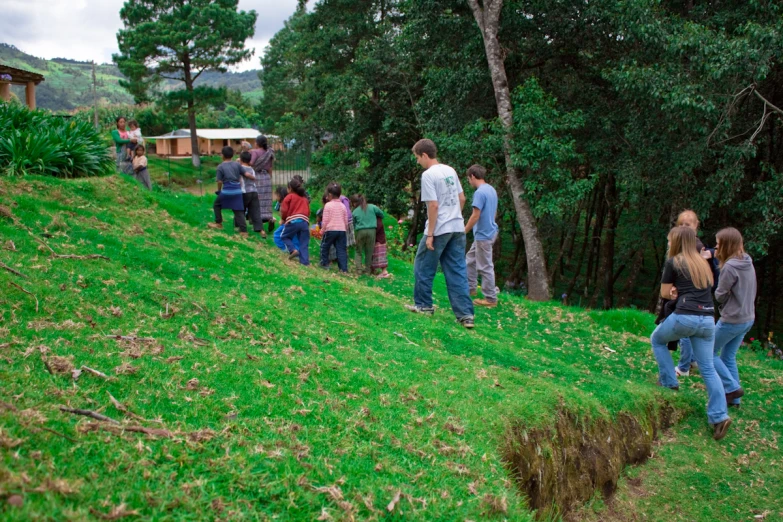 a group of people standing on the side of a green hill