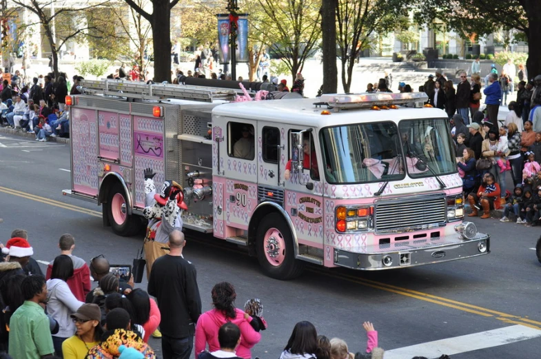 a pink firetruck driving down the street in parade