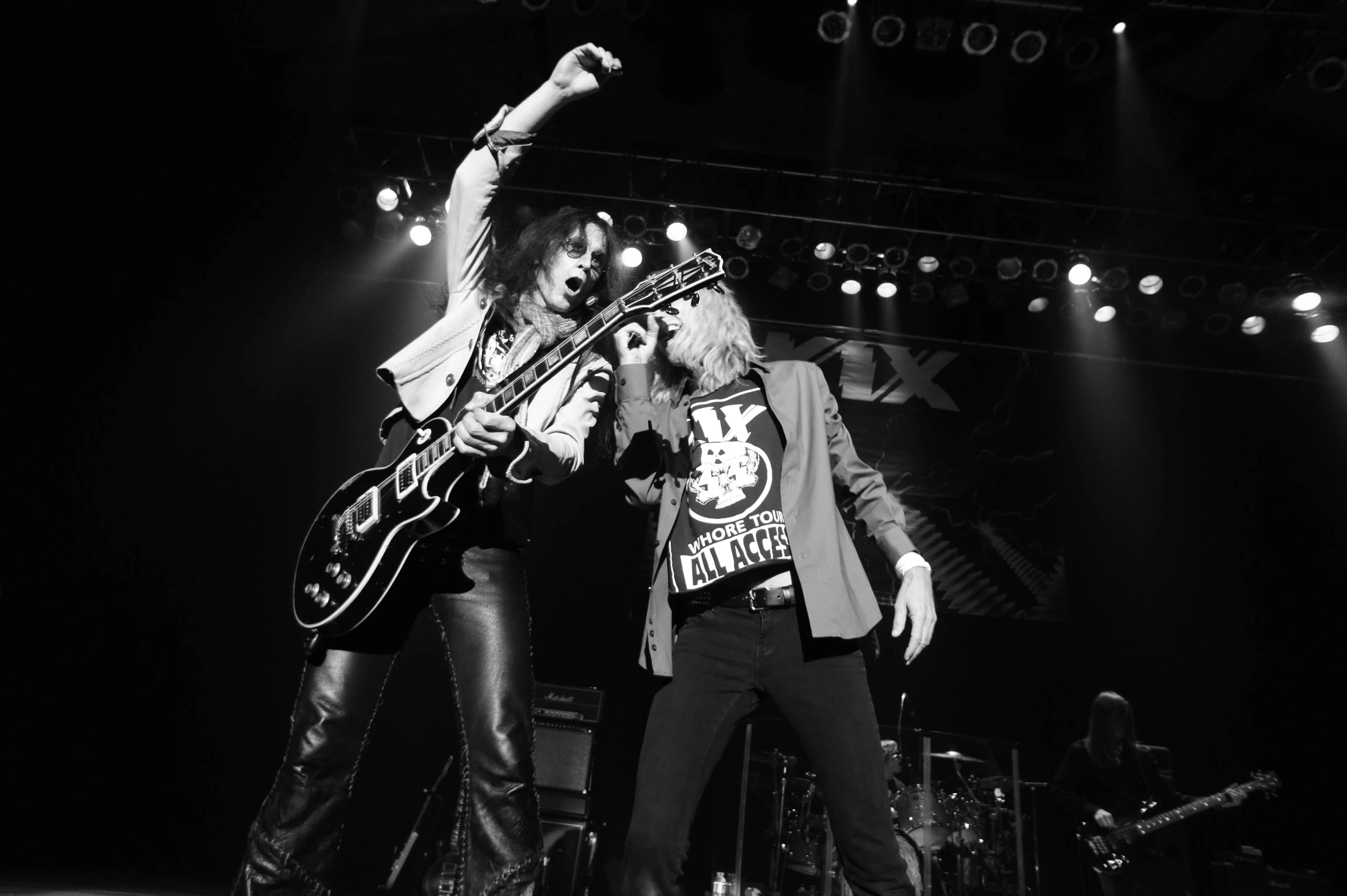 two men playing guitars on stage at night