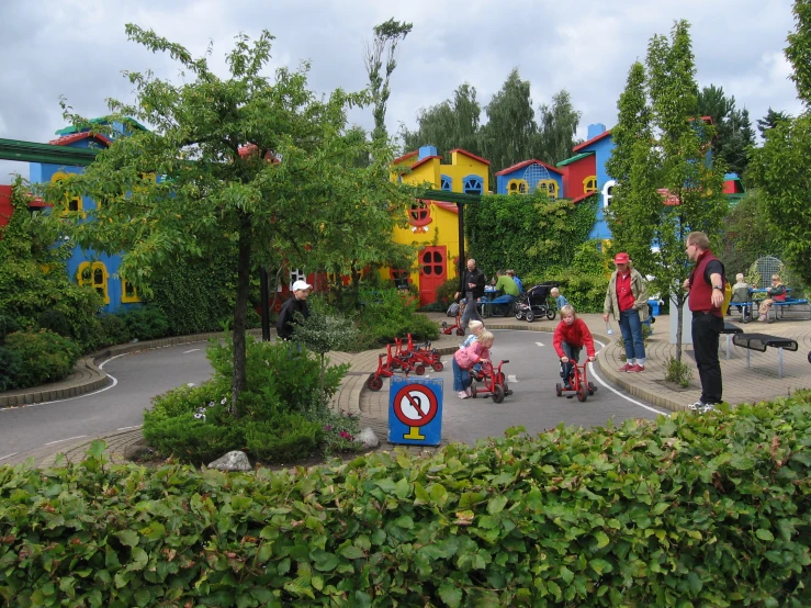 children in red shirts ride toys and on scooters in a play area