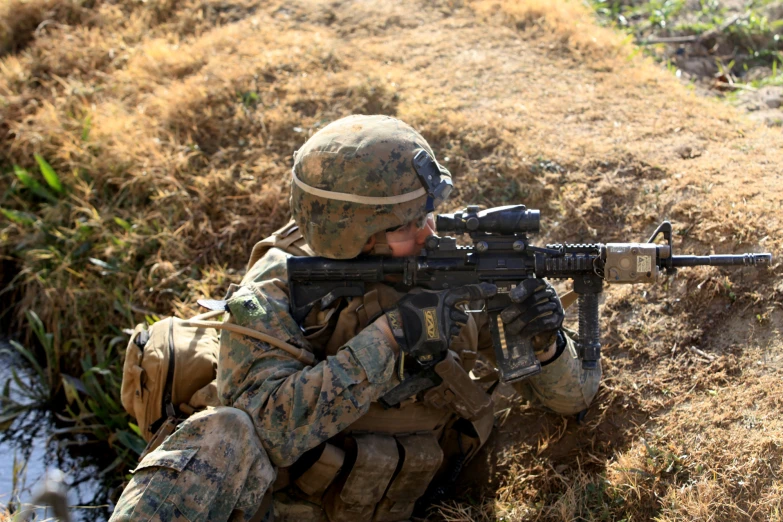 a person with a rifle crouching down in the dirt