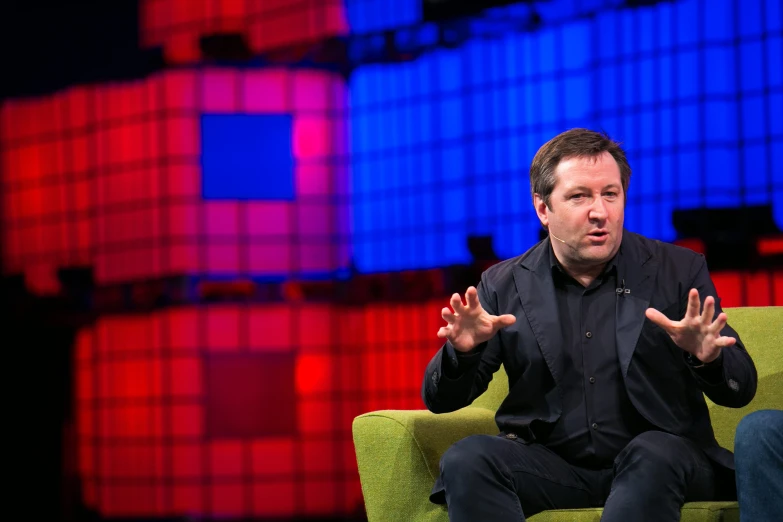 a man sits in an armchair and holds out his hands