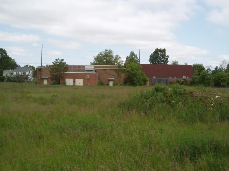 old red brick building stands behind tall grass in front of a field