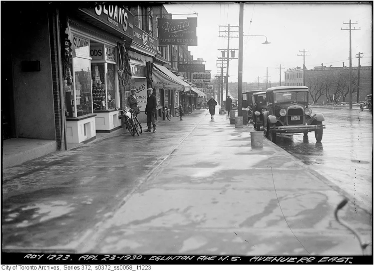 an old po shows people walking down the sidewalk