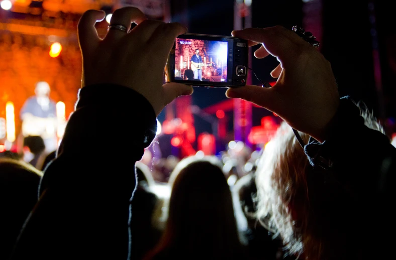 a person taking pictures with their cell phone at night