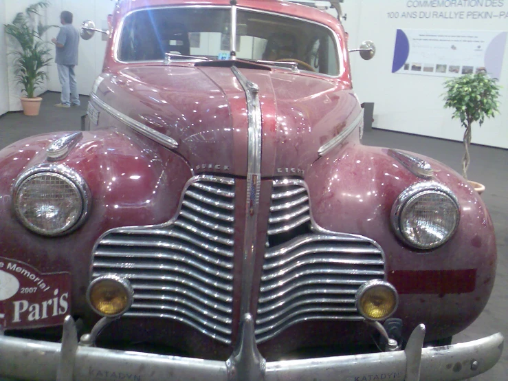 an old purple car with no wheels parked in a museum
