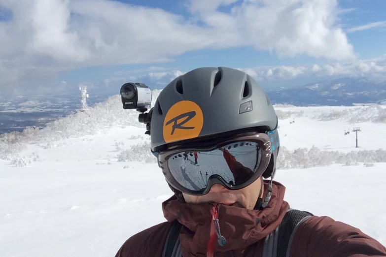 man with goggles on looking down at snow covered mountains