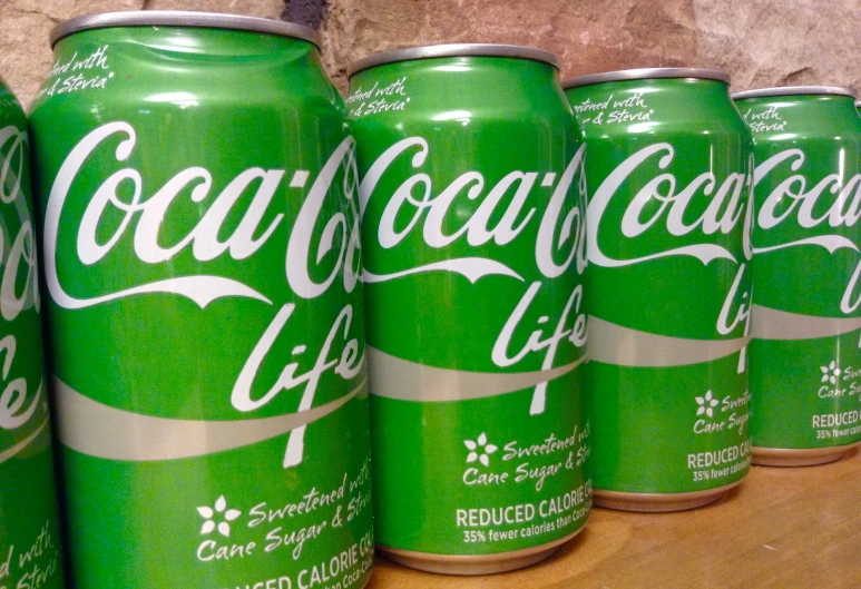 many cans of soda on a shelf near the wall